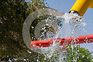 Summertime fun for the kids at the splash pad to play with water falling from bright colored yellow fountain to pool below