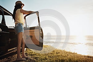 Summertime is road trip time. a young woman enjoying a road trip along the coast.
