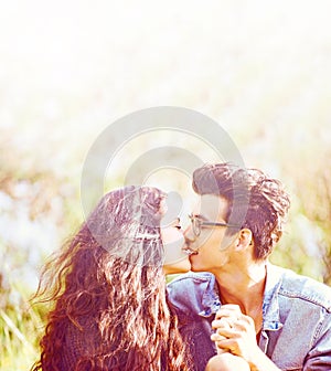 Summertime romance. Vintage style image of a young couple kissing in summer sunlight.