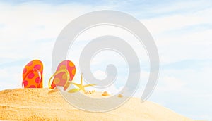 Summertime Season, colorful spotty sandals or flip-flop on sandy beach with sunny colorful blue sky background and copy space.