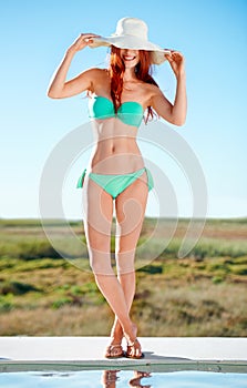 Summertime stunner. A gorgeous redhead posing in the summer sun in a bikini.