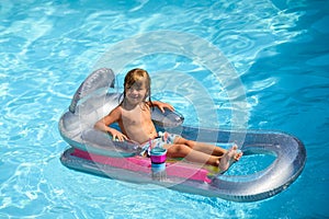 Summertime vacation. Child in pool. Boy swimming at swimmingpool. Funny kid on inflatable rubber mattress.