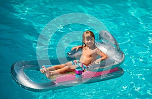 Summertime vacation. Child in pool. Boy swimming at swimmingpool. Funny kid on inflatable rubber mattress.