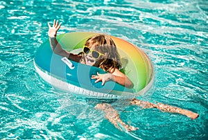 Summertime vacation. Summer kids weekend. Funny boy in swiming pool on inflatable rubber circle at aquapark.