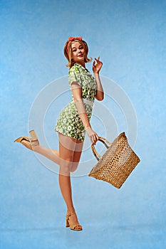 Summertime vibes. Full-length portrait of pretty young blonde girl in cute costume posing on heels with straw bag
