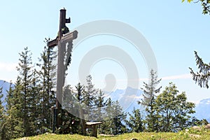 Summit cross on alpine mountain Zinkenkogel and wooden bench with blue sky in Salzburgerland, Austria