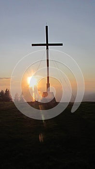 Summit cross at the mountain top at sundown