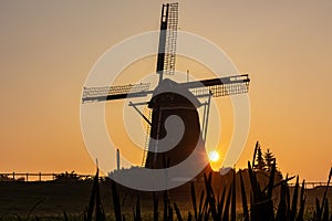 Sun appears behind a windmill in the morning mist