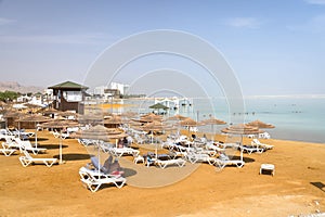 Sun beds, chairs, umbrellas and awnings on beach luxury hotel on the Dead Sea in Israel. Sunny spring day. Israeli town of Ein