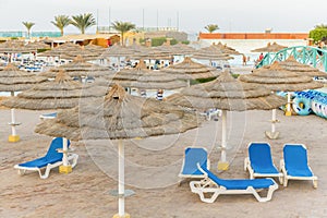 sun beds in popular tropical paradise deep turquoise mediterranean sandy beach. Umbrellas on the beach o Sea in a beautiful summer