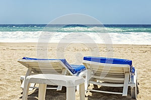 Sun beds on a sandy beach against the blue sea on a sunny windy day