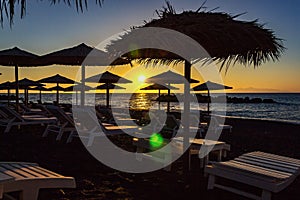 Sun beds during sunrise on beach of Kamari, Santorini, Greece