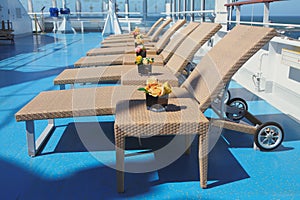 Sun beds and tables in lounge zone on deck of cruise liner