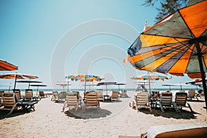 Sun beds on tropical beach with calm sky.