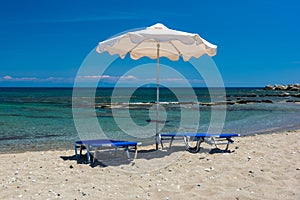 Sun beds and an umbrella on the beach, on the seashore