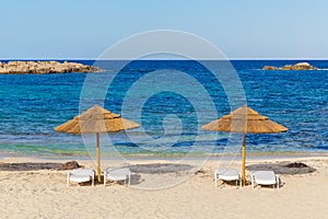 Sun beds and umbrellas on the sea coast of Formentera, Spain, the Mediterranean sea