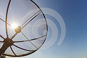 Sun behind satellite receiver with blue sky