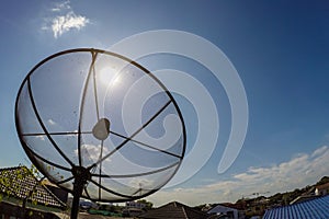 Sun behind satellite receiver with blue sky