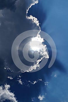 Sun behind the white clouds in the blue sky background