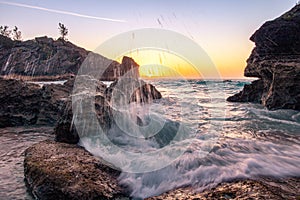 Sun breaking the horizon over a rocky cove on an  beach in Bermuda - Jobsons Cove