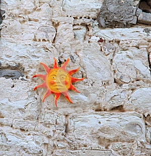 Sun ceramic sculpture on old stone wall