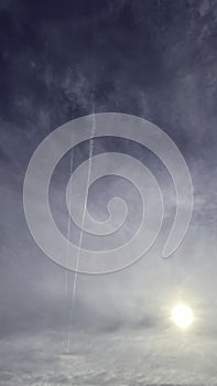 Sun, cloudy sky and vapor trail