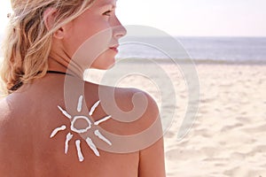 Sun cream on the female back on the beach