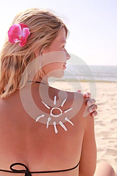 Sun cream on the female back on the beach