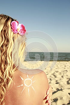 Of sun cream on the female back on the beach