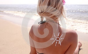 Of sun cream on the female back on the beach