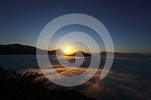 the sun at dawn with fog and backlit mountains