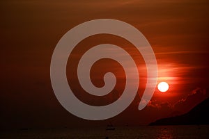 sun disk among red sky fishing boats on horizon at sunrise