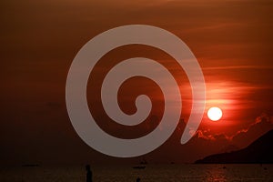 sun disk among red sky fishing boats on horizon at sunrise