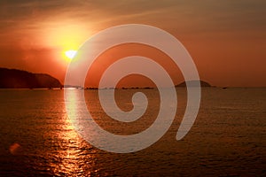 Sun disk among red sky fishing boats on horizon at sunrise