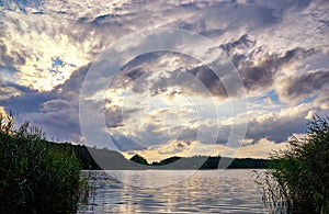 The sun at the dramatic sky over the lake. Natural background with clouds and water