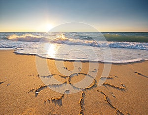 Sun drawing drawn on a beach at sunset