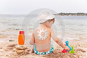 The sun drawing sunscreen on baby (boy) back.