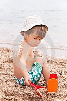 The sun drawing sunscreen on baby (boy) back.