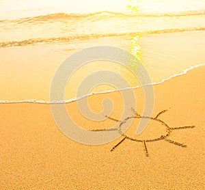 Sun drawn in the sand of a beach, soft surf wave. Travel.