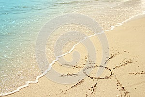 Sun drawn in the sand on the seashore