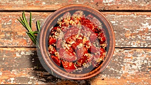 Sun dried tomatoes with fresh herbs and spices. Bowl of sun dried tomatoes garlic, oregano, olive oil on wooden background, top