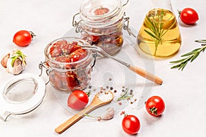 Sun dried tomatoes with fresh herbs and spices in olive oil in a glass jar Food recipe background. space for text. top view