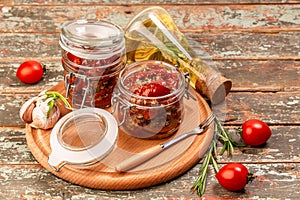 Sun dried tomatoes with fresh herbs and spices in olive oil in a glass jar Food recipe background