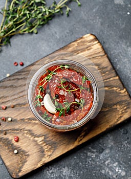 Sun dried tomatoes with fresh herbs and spices, sea salt in olive oil in a glass jar. Top view. Print for kitchen