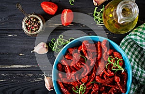 Sun dried tomatoes with herbs and garlic in bowl on wooden table.