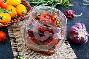 Sun-dried tomatoes with herbs, garlic in olive oil in a glass jar