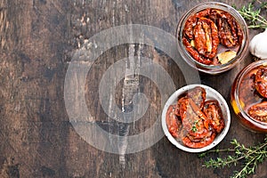 Sun dried tomatoes with olive oil in a jar on wooden background