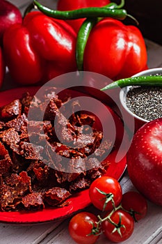 Sun-dried tomatoes with paprikas and chilly peppers on red plate