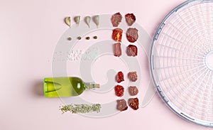 Sun-dried tomatoes with spices and olive oil on a pink background. Food knolling.