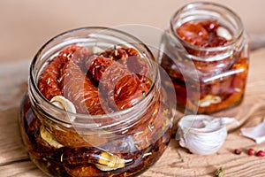 Sun dried tomatoes with thyme and sea salt in an olive oil in a glass jar on the old wooden background. Selective focus.